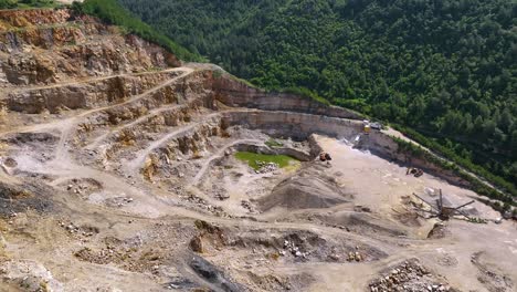 quarry and excavation hidden behind tree line in the mountains destroying the forest