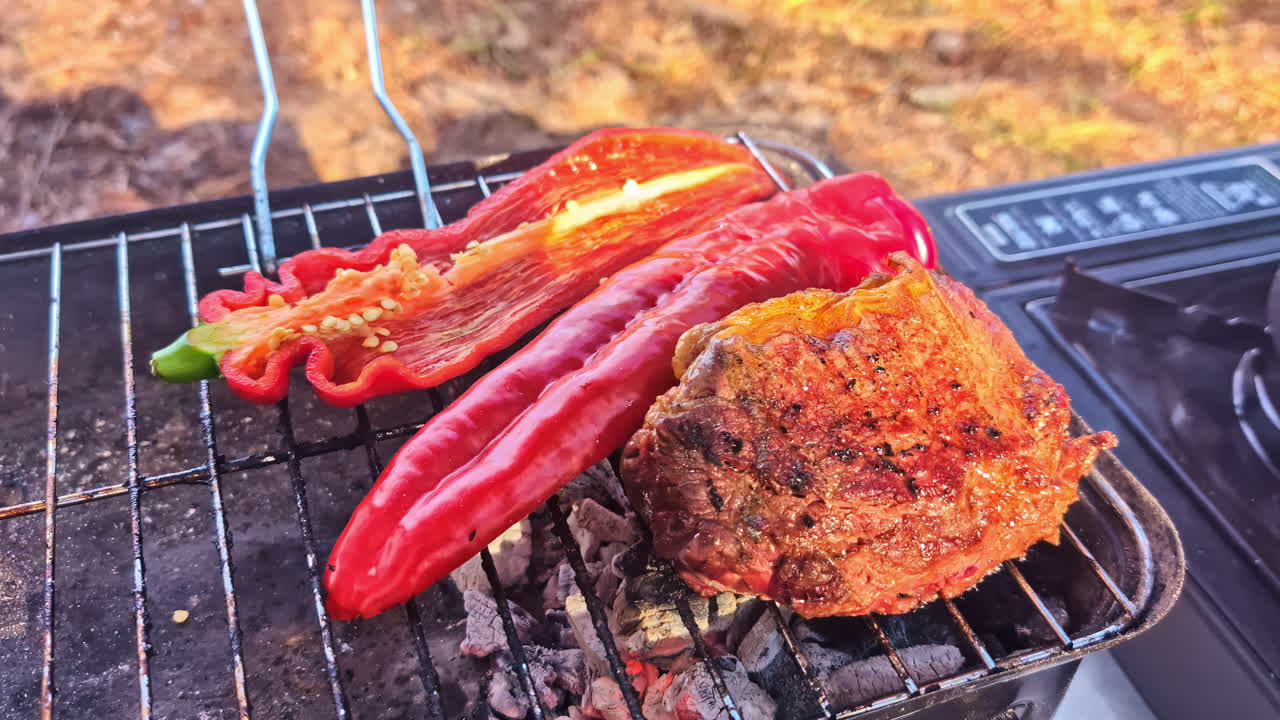 Grilled steak with sweet red peppers on open charcoal fire