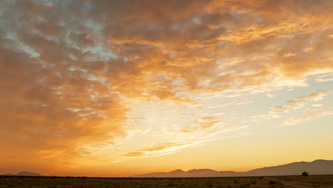 fast-moving clouds glow from golden to pink as the sunset glows over the mojave desert landscape