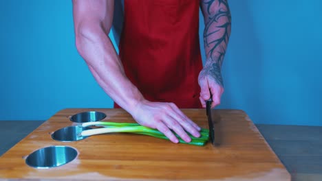 chef cortando cebolla en la tabla de cortar, de cerca, manos tatuadas