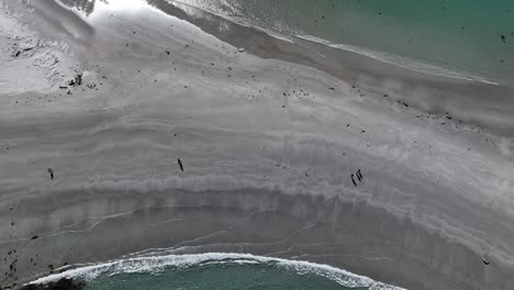 people walking on sandy path connecting diamond island at beach, tasmania in australia. aerial top-down view and slow-motion
