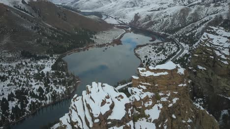 Drone-Cruza-Sobre-Un-Gran-Monte-Rocoso-Para-Luego-Ver-Un-Paisaje-Nevado-Con-Un-Camino-Que-Lo-Recorre