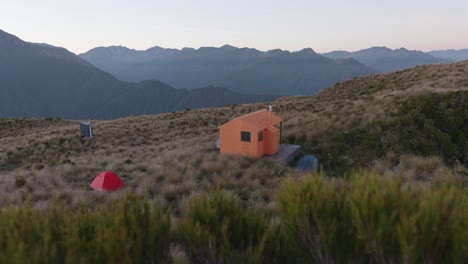 pequeña cabaña y tiendas de campaña en las montañas durante el amanecer en mt brown, costa oeste, nueva zelanda
