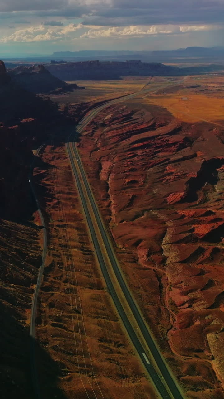 Flying above the motorways at the foot of fascinating canyons. Spectacular view of rocky relief from aerial perspective. Vertical video