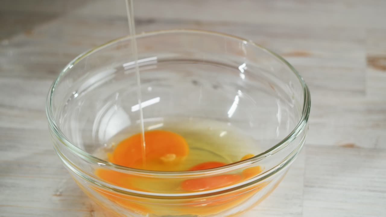 Hands Cracking Fresh Eggs into a Glass Bowl