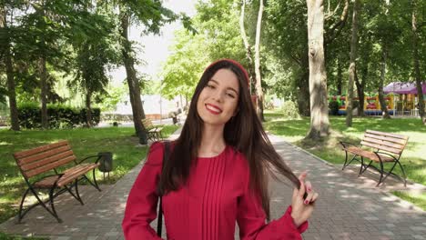 alegre chica positiva en rojo camina en un hermoso parque
