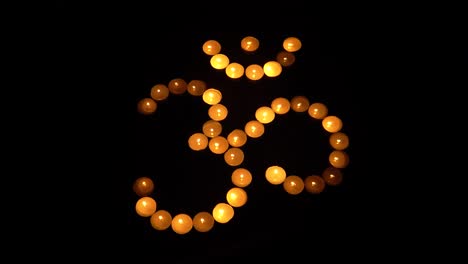 om symbol from burning candles on black background, for meditation and mantra