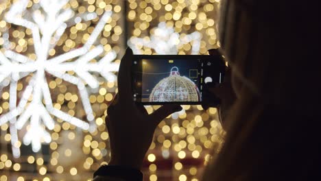 Frau,-Die-Nachts-Mit-Einem-Telefon-Eine-Weihnachtsdekoration-Fotografiert