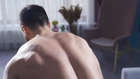 젊은 보디빌더는 집에서 덤벨을 사용하여 허리 근육을 운동합니다.