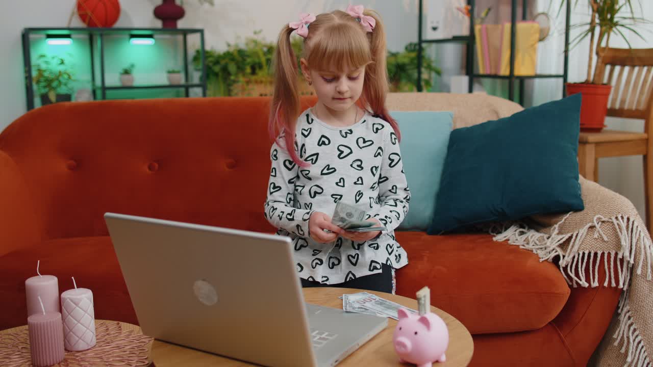 niña pequeña contando dinero billetes de dólar para necesidades futuras en el escritorio de casa con computadora portátil, alcantarillado