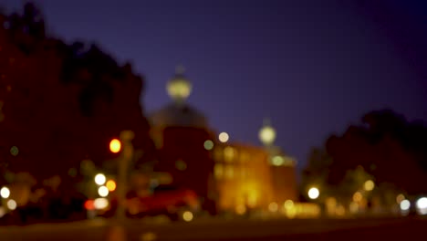 ancient city square at night with cars and motorcycles passing by in out of focus