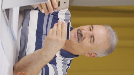 video vertical de un trabajador de oficina en casa, un anciano comprando por teléfono.