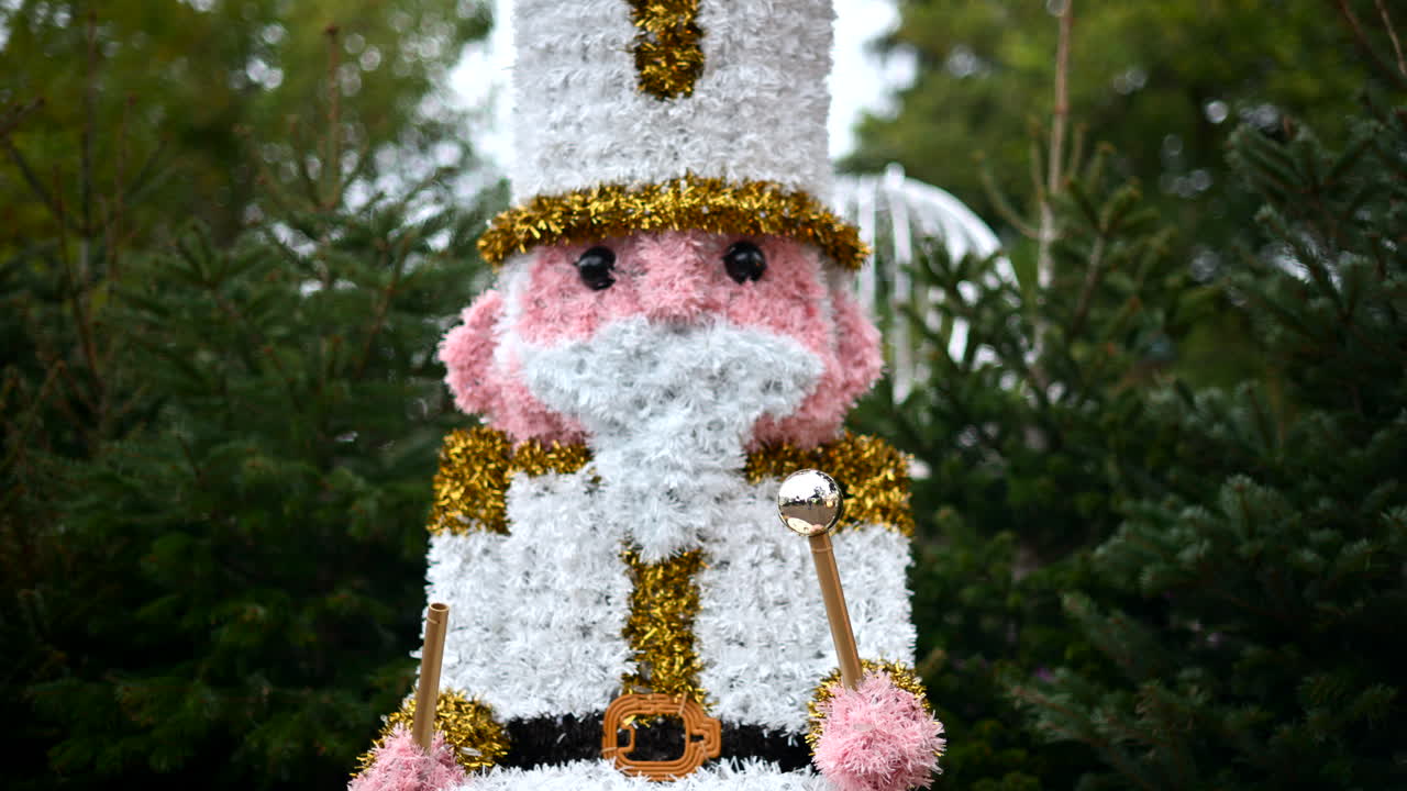 Decorative Christmas nutcracker soldier figure displayed outdoors with trees in the background