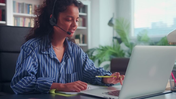 Young indian woman with headset sitting at home getting education online