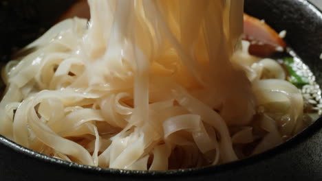 primer plano de un tazón de sopa de fideos de vidrio con palillos
