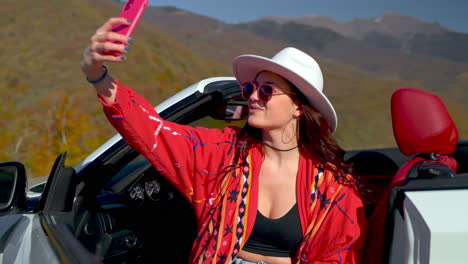 woman taking selfie in a convertible car on a scenic road trip