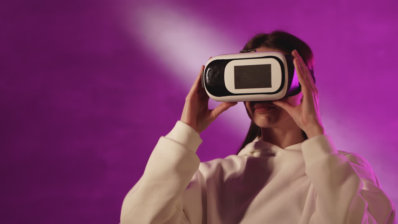 화려한 네온 조명 배경에서 가상 현실 안경을 사용하는 여성