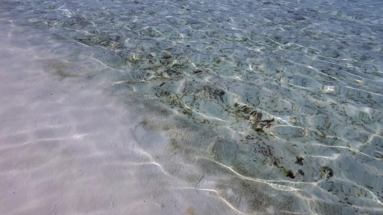 песчаное дно под волнистой морской поверхностью на белом песчаном пляже