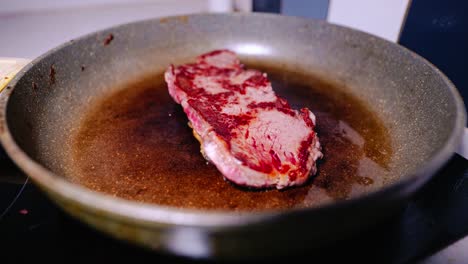 timelapse showing raw steak sizzling in frying pan and beginning to brown evenly