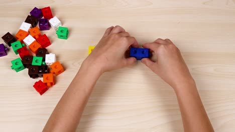 hands assembling colorful linking cubes on table