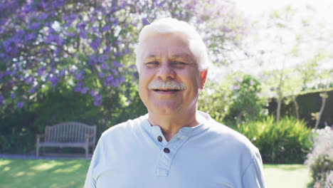 retrato de un hombre caucásico mayor feliz con bigote sonriendo en el jardín, en cámara lenta