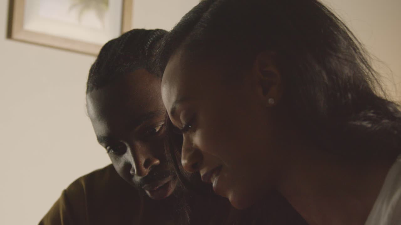 pareja joven relajándose en casa por la noche en el dormitorio mirando el teléfono móvil juntos 1