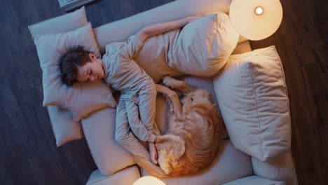 child and golden retriever sleeping peacefully on a couch