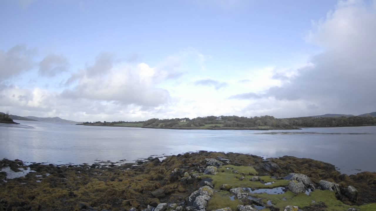 아일랜드 도네갈 카운티 크리슬로프 근처의 미상 성에서 물 위로 구름이 흩날리는 패닝 시간 경과