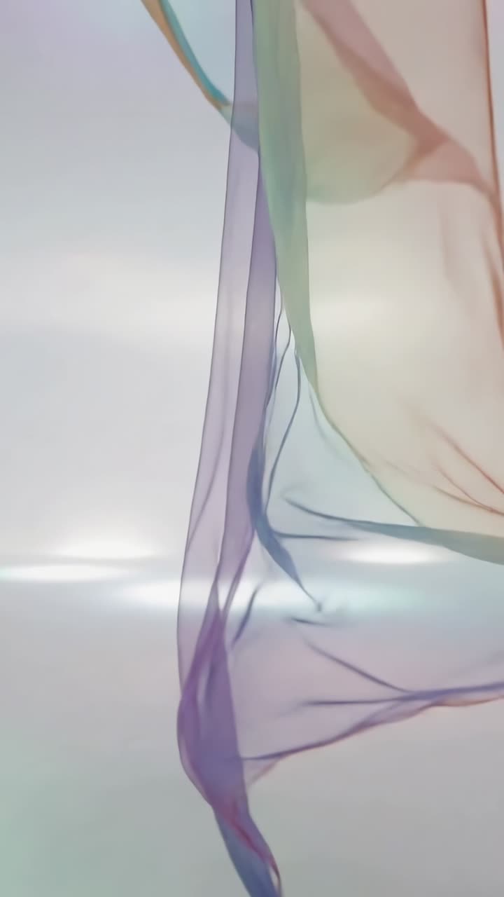 Vertical video: Entering scarf drifting in pale set showing hues light pools blue prop, copy space