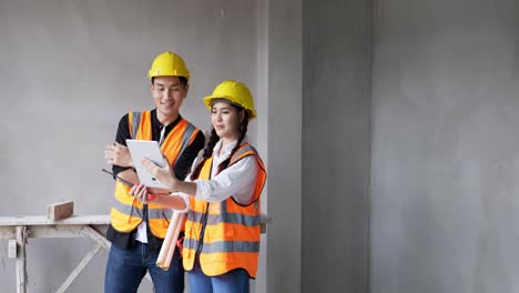 desde el trabajo en un sitio de construcción en el interior, una joven mujer y un capataz con chalecos naranjas y cascos de seguridad están haciendo llamadas de video en sus tabletas.