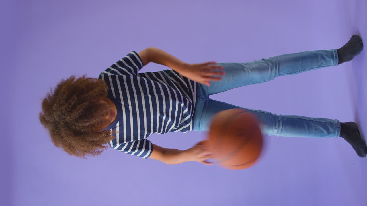 Video Vertikal Anak Laki-laki Menggiring Bola Basket dengan Latar Belakang Ungu