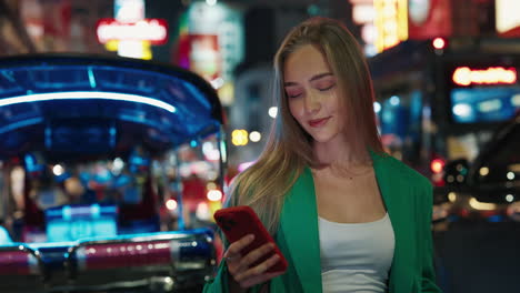 mujer usando el teléfono en una ciudad por la noche