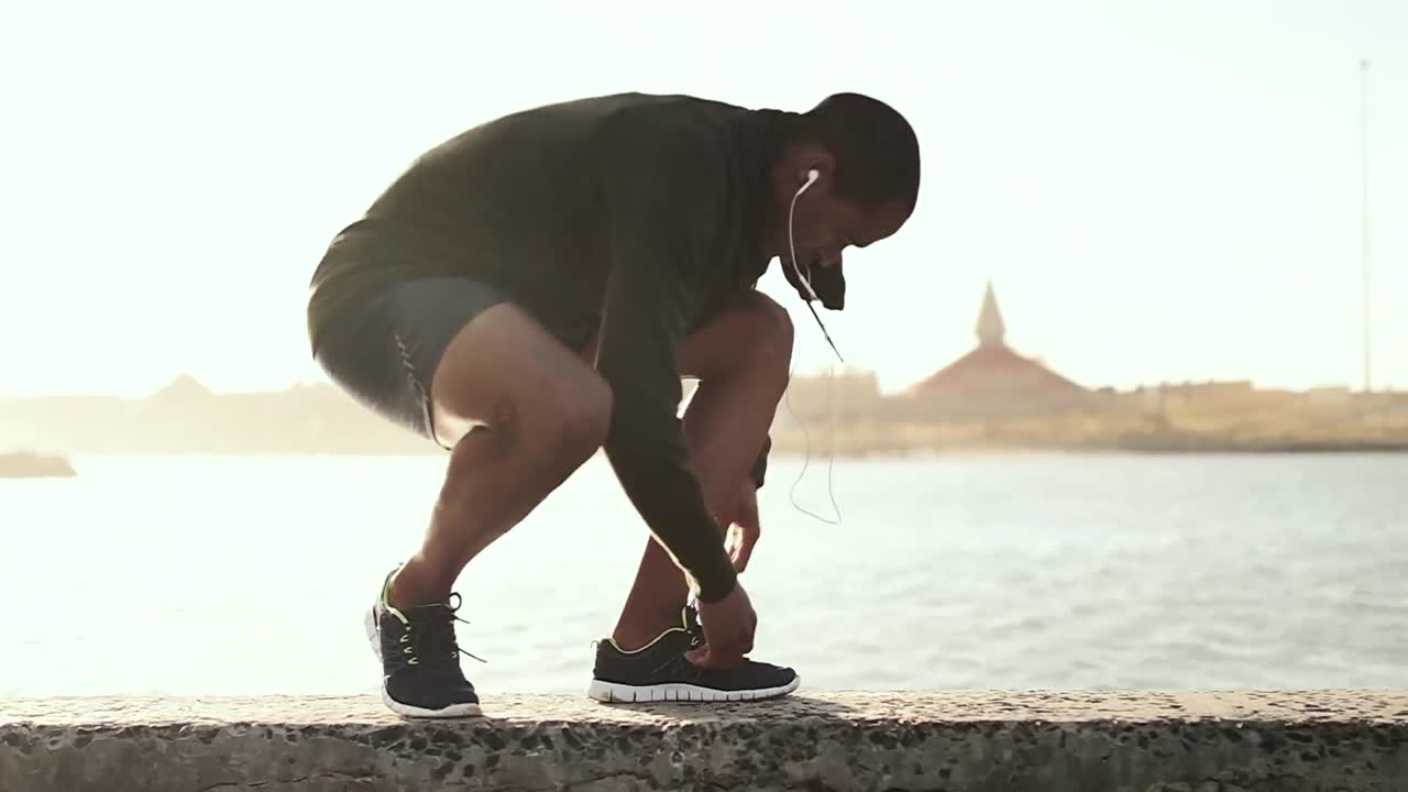 Man tying his shoe laces while running on the promenade