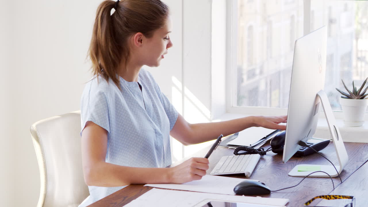joven blanca contestando el teléfono en su escritorio de la oficina