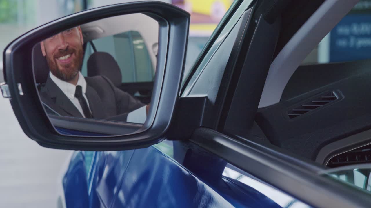 hombre de negocios feliz sentado en un coche nuevo y mostrando el pulgar hacia arriba