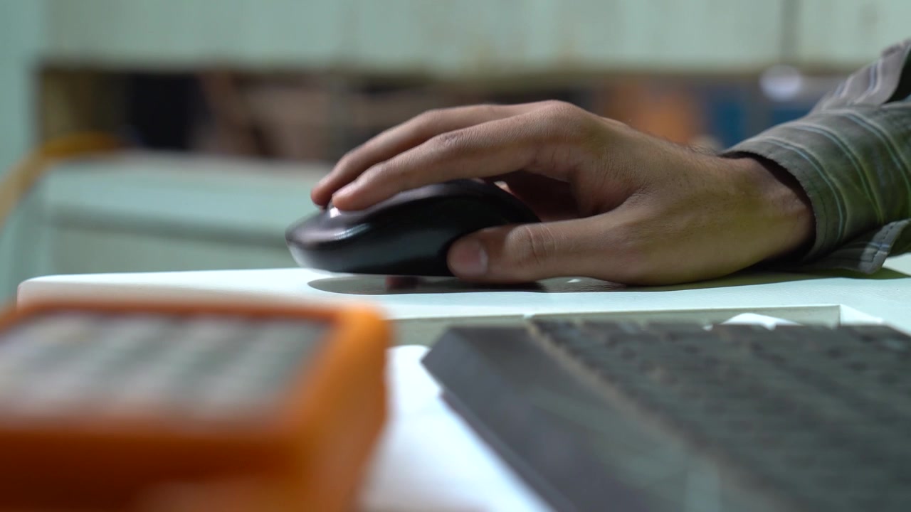 Tecnico di macchine CNC che usa un mouse del computer per programmare una procedura in un'officina metallurgica industriale