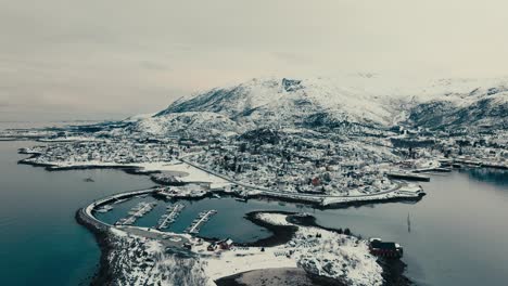 snow mountains and harbour in lodingen fishing village in lofoten, norway. aerial drone shot