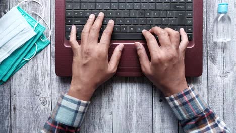 person working on laptop with masks and sanitizer