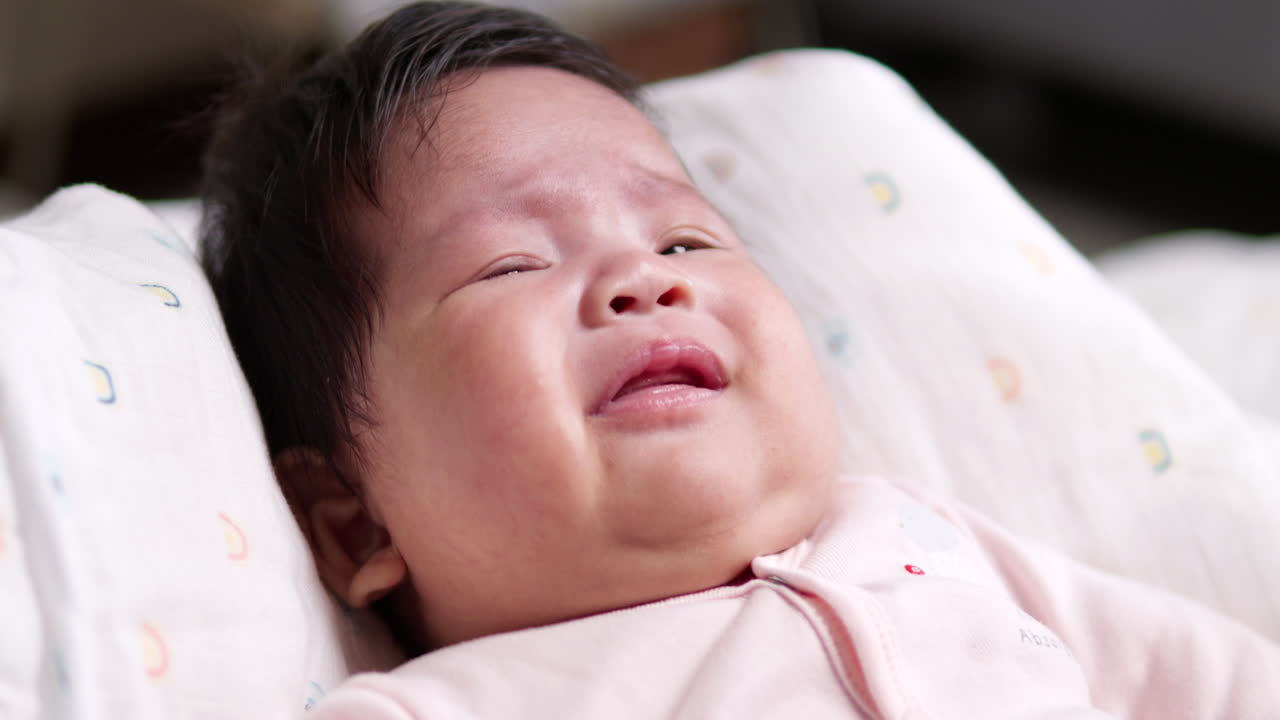 Moving its head from one side to the other, the newborn child broke into a cry as it stretches its arms and legs while her chubby cheeks turned red