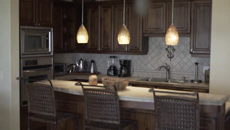 kitchen with wooden furniture next to microwave oven, bamboo chairs and hanging light fixture