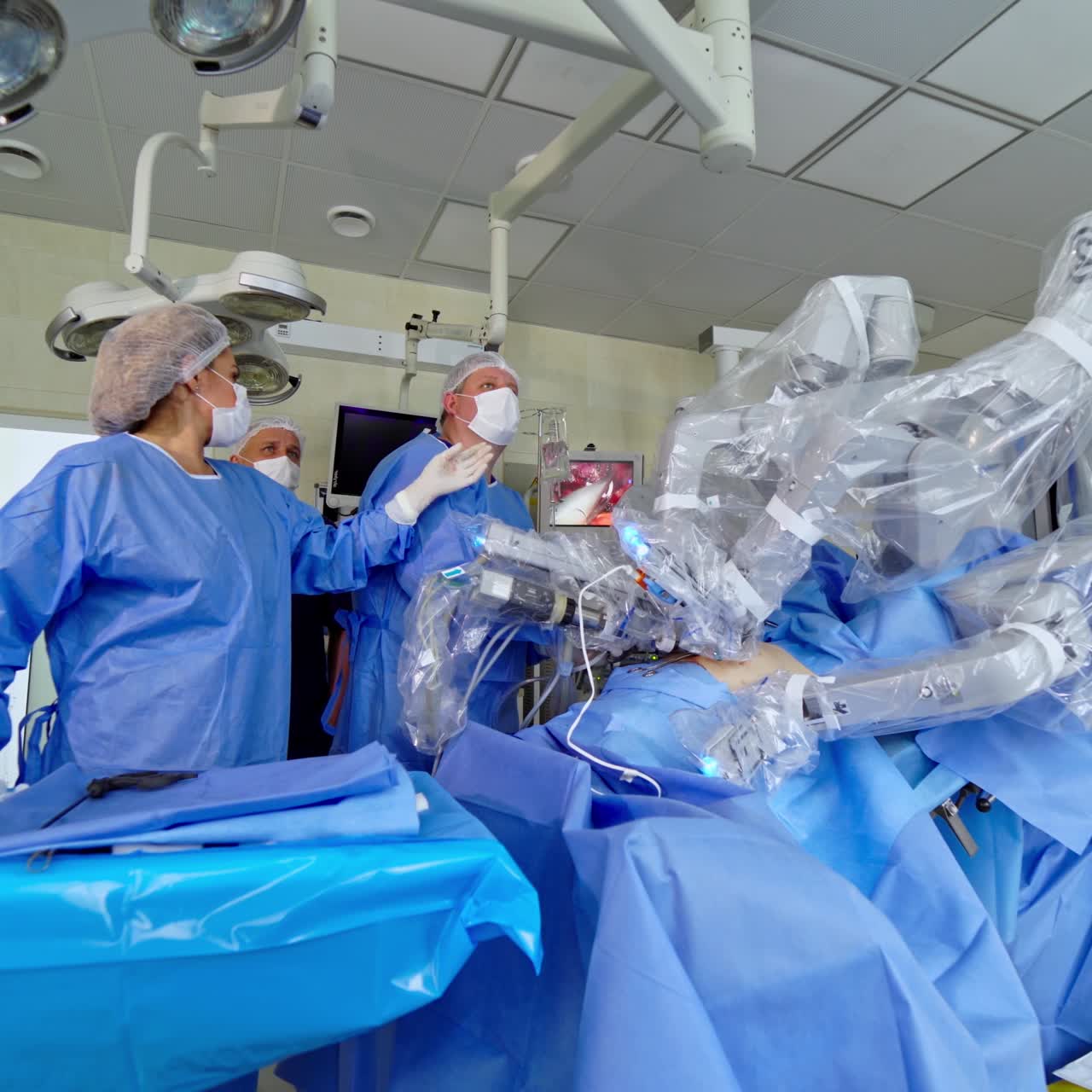 Robotic surgery in sterile operating room. Group of doctors observe the work of medical robot performing surgery in hospital. Minimally invasive operation in modern clinic