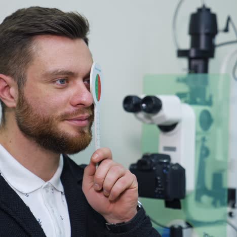 close-up portrait of man during test on refractometer machine. video from side. eye exam for man at optical store