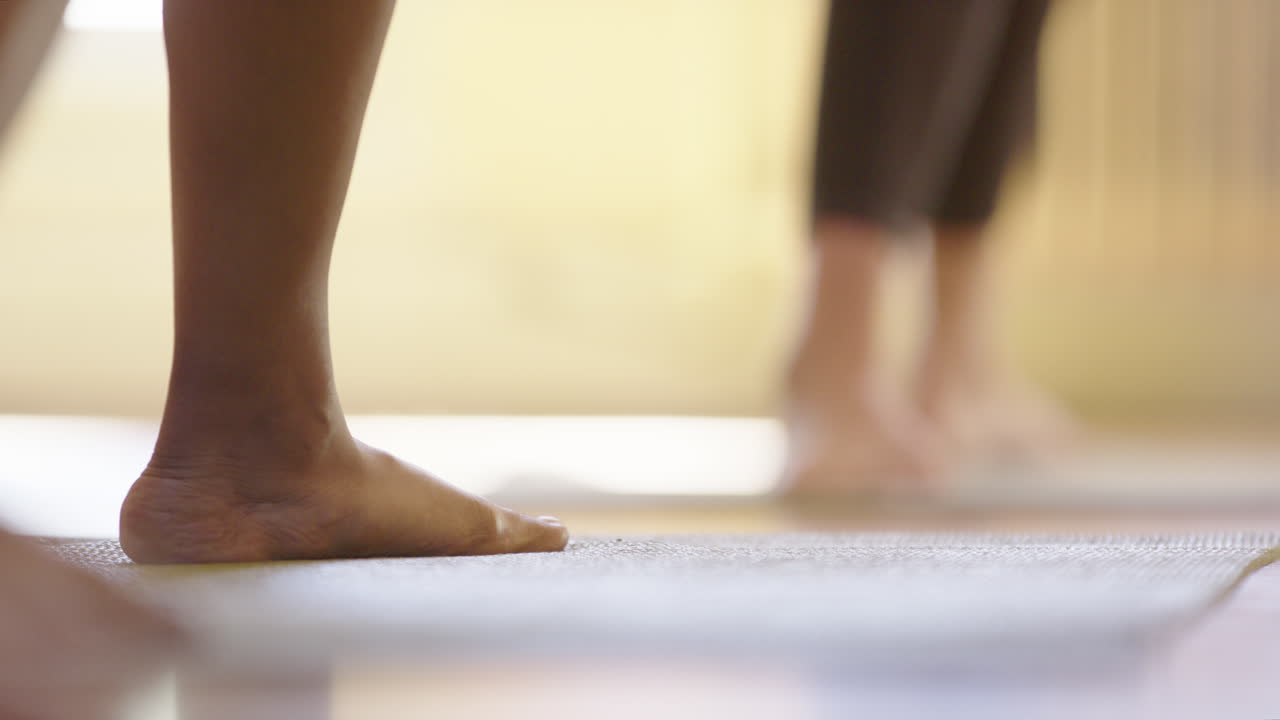 Rack focus of different feet on a mat doing yoga postures