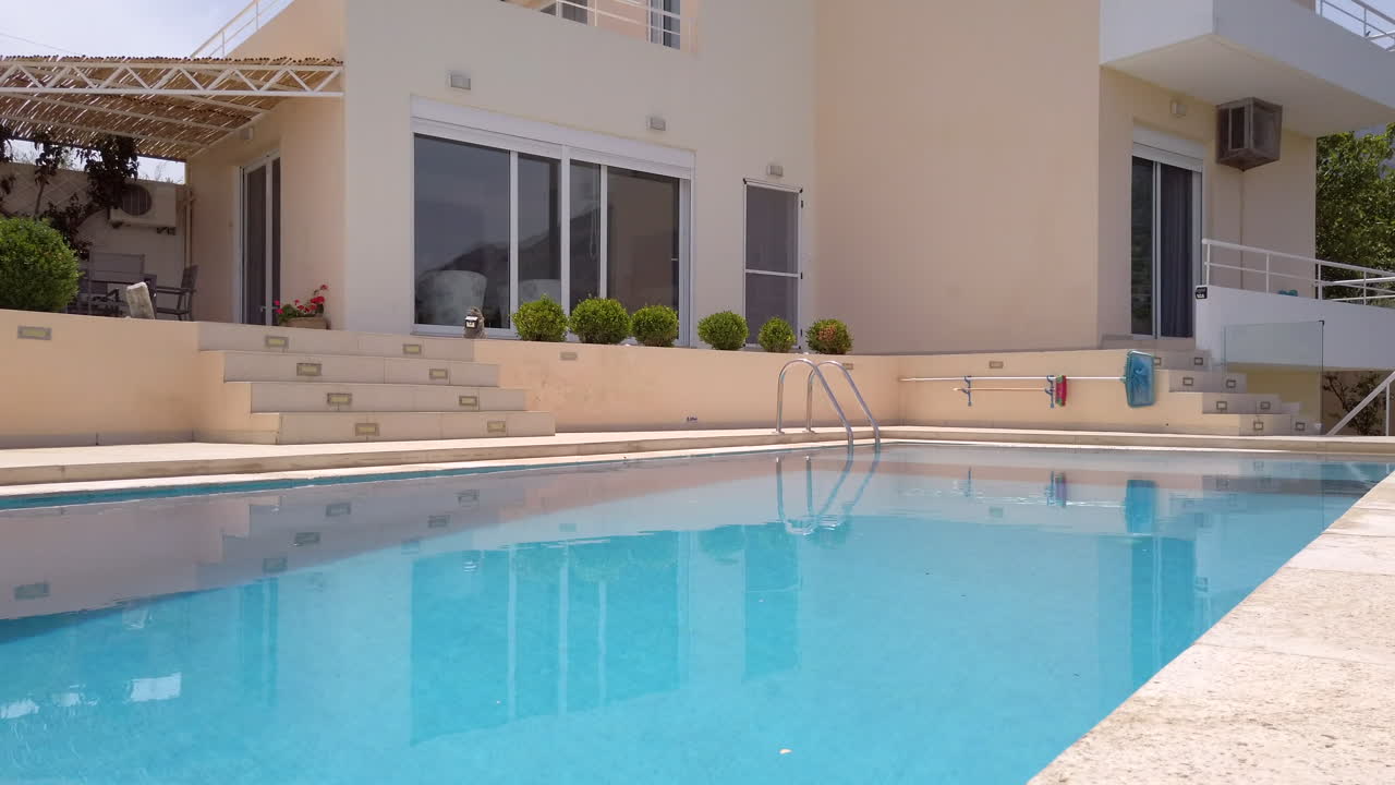 Fading In Tilt Shot Revealing Luxury Greek Villa with Pool on Sunny Day with Blue Sky
