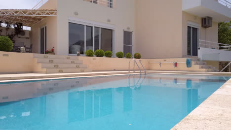 fading in tilt shot revealing luxury greek villa with pool on sunny day with blue sky