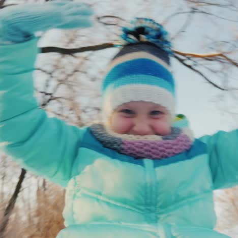 Cheerful-Little-Girl-Goes-On-A-Sled-Claps-His-Hands-Is-Happy-Winter