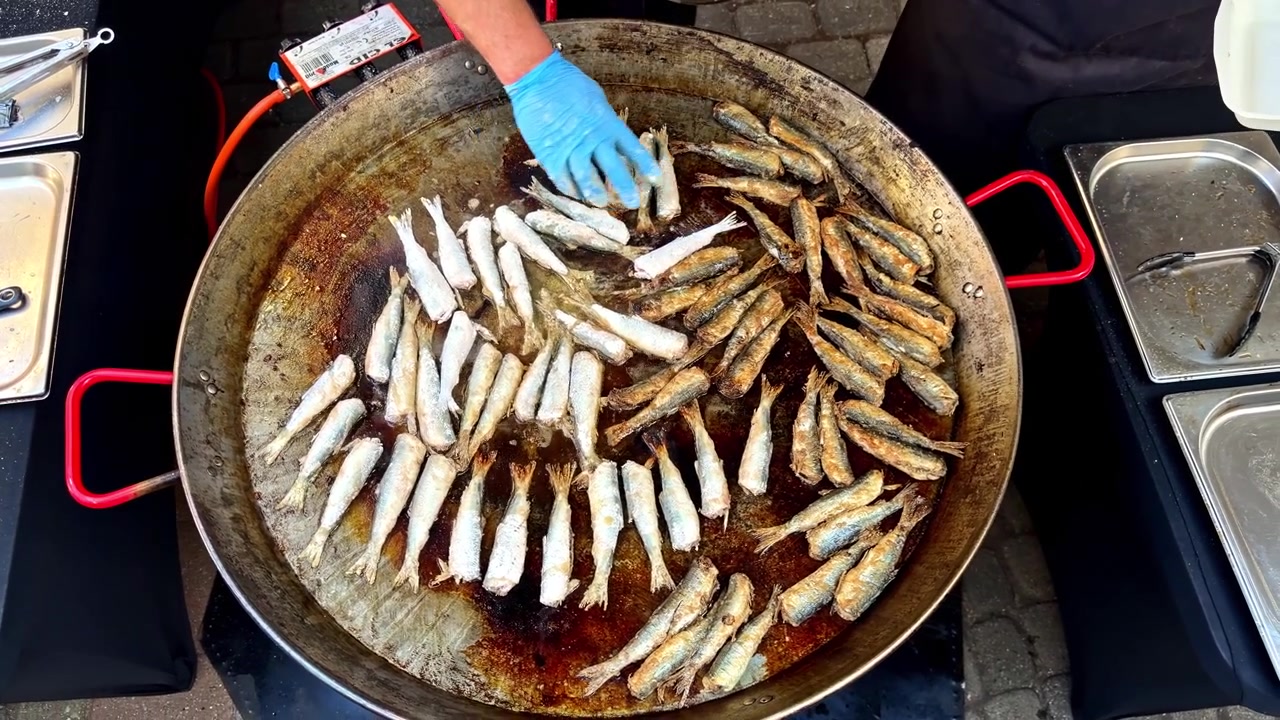 Small Fish are Being Fried in a Large Pan, cooking Evenly Over Hot Oil - Close Up