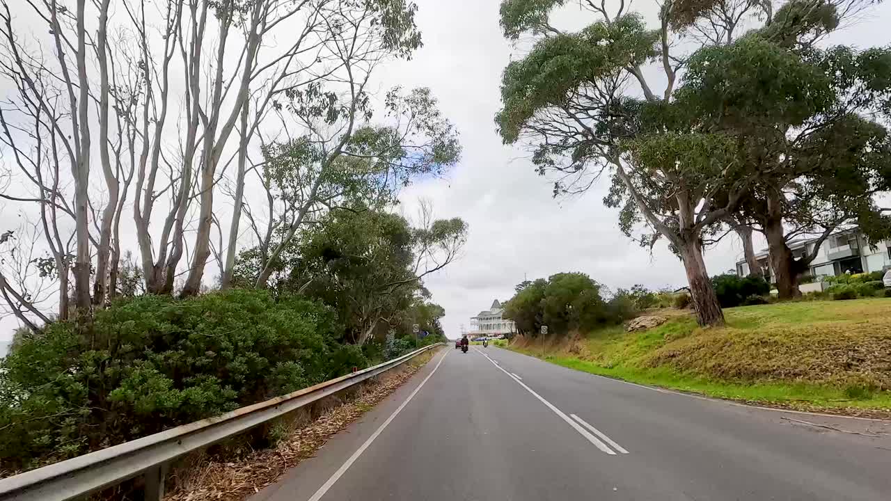 A drive through lush greenery and coastal views on Great Ocean Road, under overcast skies, capturing serene landscapes and winding roads
