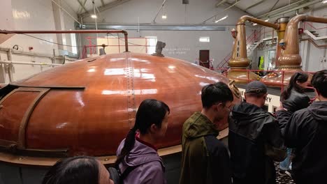 visitors explore copper stills in a distillery