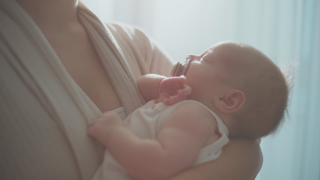 Mother holding sleeping baby in baby carrier